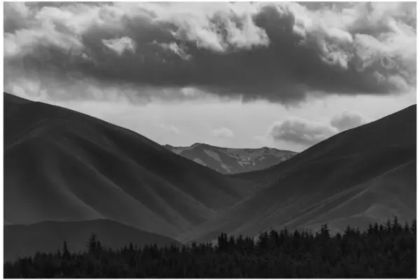 Black and white of mountain range with clouds overhead